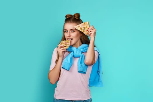 happy woman holding two slice of fresh pizza on blue background.