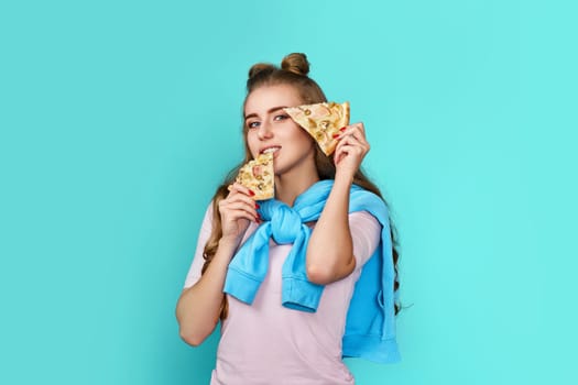 beautiful happy woman covering her eyes with slice of fresh pizza on blue background.