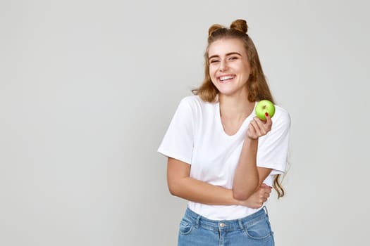 smiling pretty girl holding green apple isolated on studio background. copy space