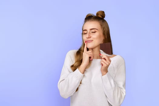 lovely pretty charming cute dreamy woman enjoying dark chocolate isolated on pastel violet background. copy space