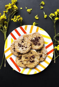 Oatmeal cookies with chocolate on a plate with bright yellow flowers