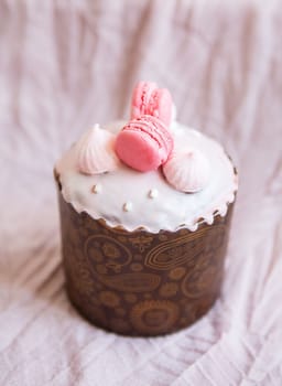 A traditional paska decorated with pink swiss chocolate and meringue stands on a pink tablecloth. Easter holiday, top view. Place for writing