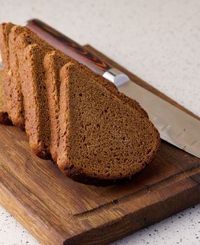 Triangular rye piece of bread on a wooden cutting board