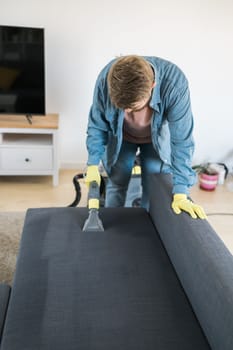 Man cleaning couch with washing vacuum cleaner