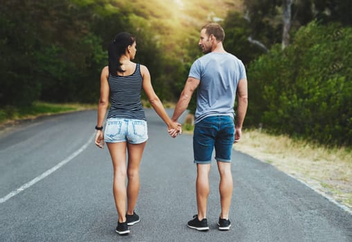 Love knows the way. a happy young couple walking down a road outside