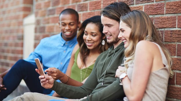 Good friends share cool things with each other. a group of young friends using a mobile phone together