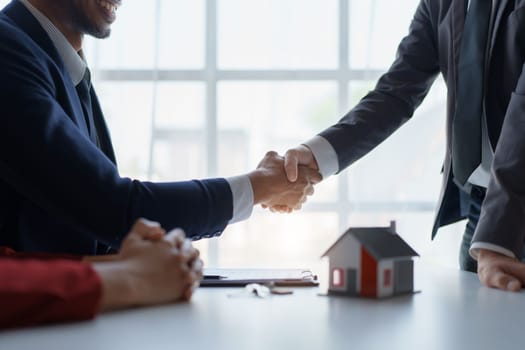 Asian real estate agent shaking hands handing over house and keys to his client's house after client sign contract