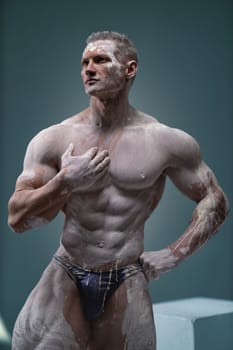 Studio shot of a muscular man. Young handsome athletic caucasian guy with beautiful naked torso looking away while posing shirtless isolated over grey background. Sports workout concept