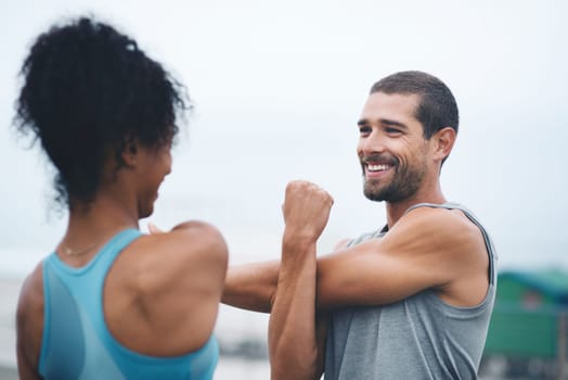 Friends in fitness. two sporty young people stretching while exercising outdoors