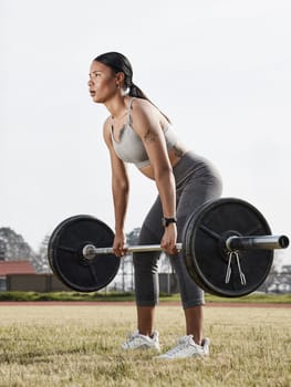 Be the best version of you. a young woman using a barbell while exercising outdoors