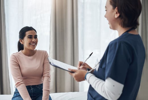 Just keep smiling. a young female doctor writing down a patients information in an office