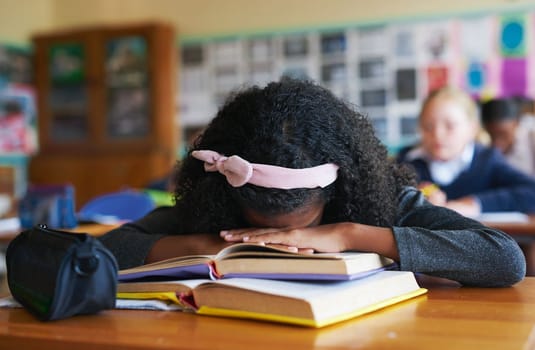 I just want to go home. an unrecognizable girl asleep on her text books in her classroom at school during the day