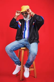 Im getting old but I still dress good. Studio shot of a senior man wearing retro attire while posing against a red background