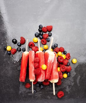 Melt in your mouth goodness. Studio shot of berry ice lollies surrounded by an assortment of berries