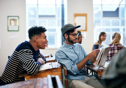 Helping each other will help understand things better. university students going through notes together in class