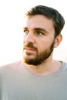 Portrait of a young man with a beard looking into the distance. High quality photo