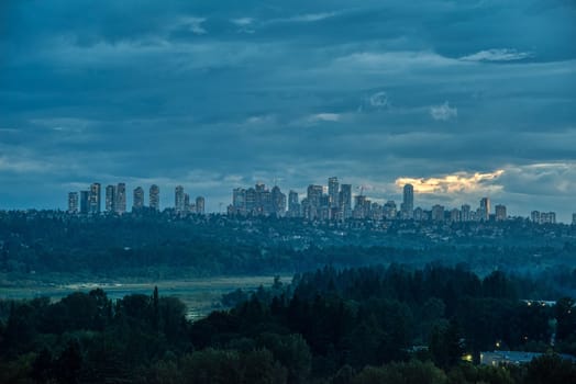 Scenery view of Metrotown cityscape over Burnaby lake on cloudy sky background