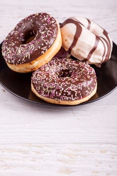 Different type of donuts on white wooden background. Delicious junk food