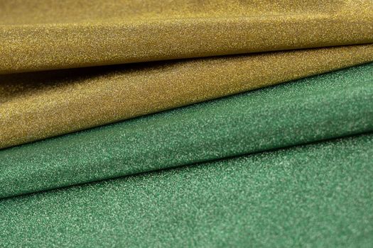 Golden and green wave shiny glitter paper texture. Shining luxurious fabric. Glimmering light green golden color, christmas background