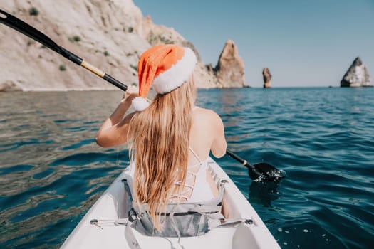 Woman in kayak back view. Happy young woman with long hair floating in transparent kayak on the crystal clear sea. Summer holiday vacation and cheerful female people relaxing having fun on the boat