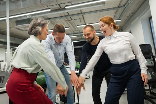 Four colleagues give the low five in the office