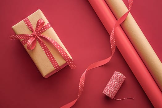 Gifts preparation, birthday and holidays gift giving, craft paper and ribbons for gift boxes on coral background as wrapping tools and decorations, diy presents as holiday flat lay design.