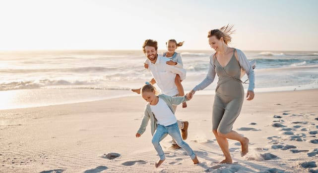 Carefree family playing on the beach together. Happy family on vacation by the ocean together. Little girls playing with their parents on holiday. Caucasian family bonding on the beach.