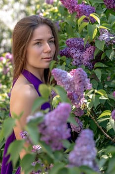 portrait of young woman with long hair outdoors in blooming lilac garden.