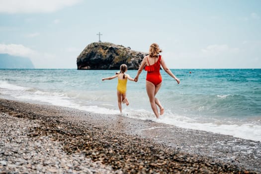 Happy loving family mother and daughter having fun together on the beach. Mum playing with her kid in holiday vacation next to the ocean - Family lifestyle and love concept.