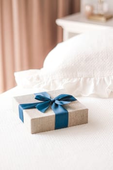 Holiday present and luxury online shopping delivery, wrapped linen gift box with blue ribbon on bed in bedroom, chic countryside style, close-up