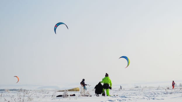 people kiting in winter in snowy terrain. snowkiting.