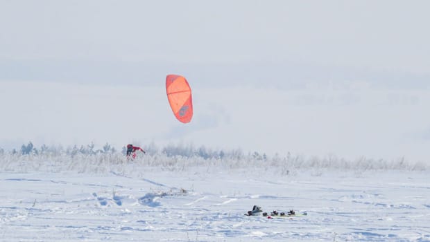 people kiting in winter in snowy terrain. snowkiting.