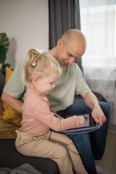 People with cochlear implant system. Kid study to hear with father, learning with video on tablet. Installation cochlear implant on child girl ear for restores hearing.