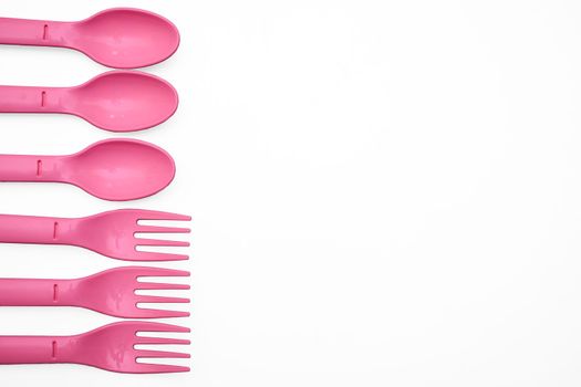 put, lay, or stand something in a specified place or position. Pink plastic camping spoons and forks isolated on white.