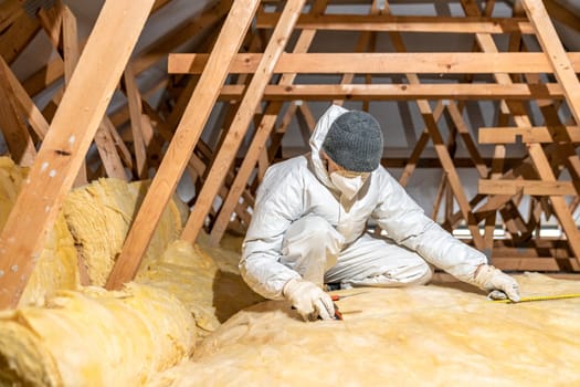 a man insulates the roof and ceiling of the house with glass wool