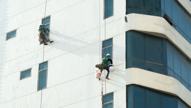 Industrial climbers paint high-rise walls and wash windows. High quality photo
