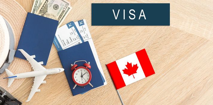 Flag of Canada with passport and toy airplane on wooden background. Flight travel concept.