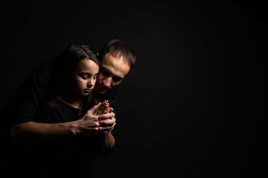 Young father and daughter praying with hands together with hope expression on face very emotional and worried