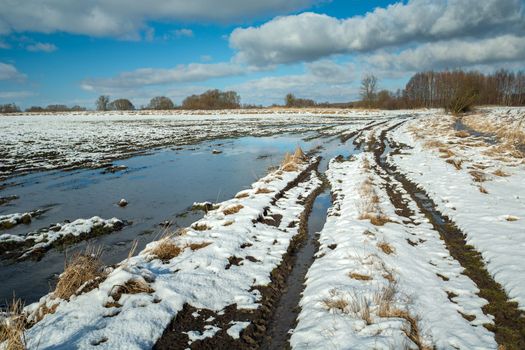 Melting snow on the field and rural road, Zarzecze, Poland