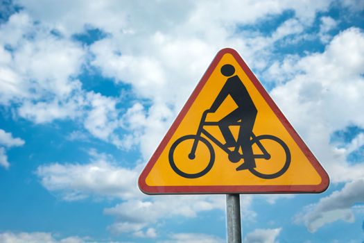 Yellow-red road sign cyclists against the blue sky