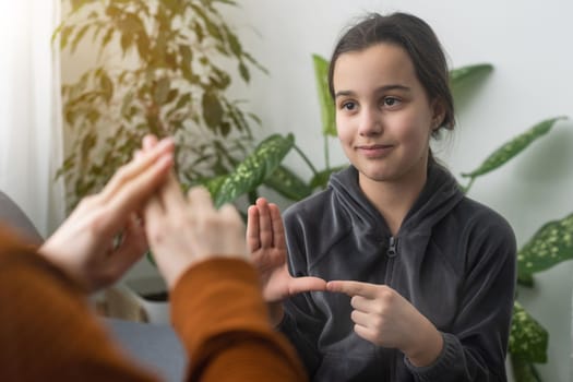 Small Caucasian teen girl child do articulation exercises with caring mother or teacher at home. Little kid pronounce sounds speak talk with tutor or coach, engaged in voice pronunciation together.