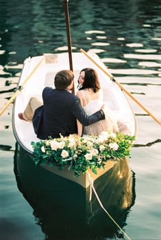 Man and woman sit embracing in a boat decorated with flowers. High quality photo