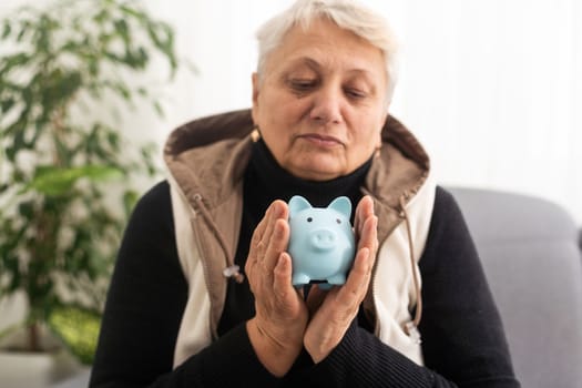 Close-up shot of elderly woman holding pig money-box. Senior woman hands holding a piggybank. Concept of saving money for old age