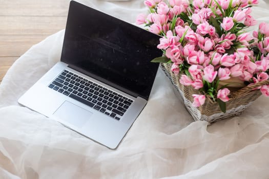 Table with laptop and flowers in a basket.