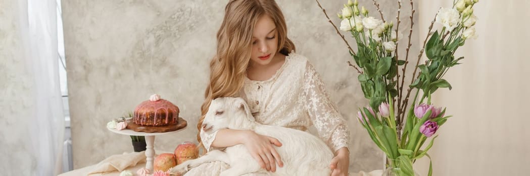 A girl with long hair in a light dress is sitting at the Easter table with cakes, spring flowers and quail eggs. Happy Easter celebration