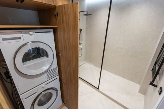 Marble laundry room interior with wooden countertops, a closet and built in washing machines.