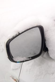 Side mirror of the car in the snow close up