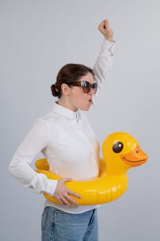 Excited woman in white shirt dreaming about vacation, wearing sunglasses and inflatable duck