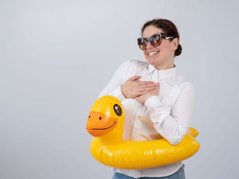 Caucasian woman in a white shirt dreaming of a vacation and wearing sunglasses and an inflatable duck