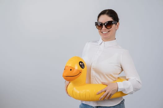 Caucasian woman in a white shirt dreaming of a vacation and wearing sunglasses and an inflatable duck
